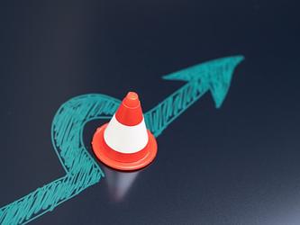 green arrow going around an orange cone